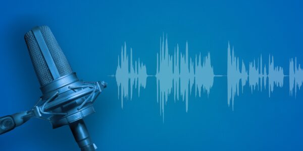 Retro microphone with a metal grille on a blue background alongside white audio waveforms, conveying a podcast or broadcasting theme.